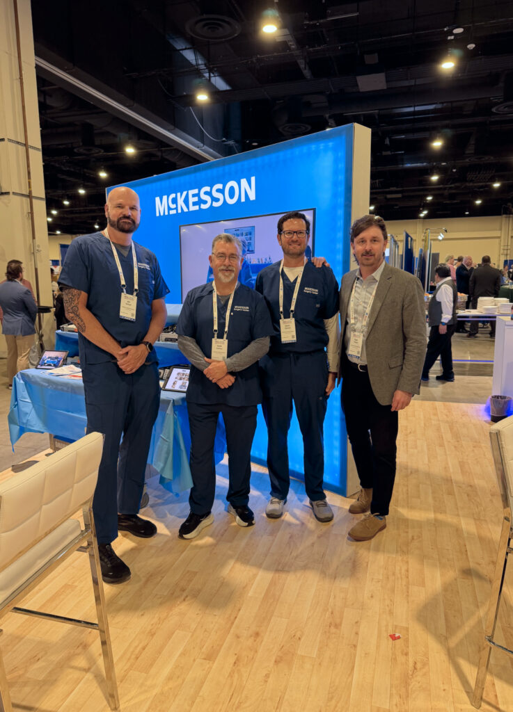 Attendees in the McKesson booth posing for a group picture with the Mckesson rep in front the of the DinamicOR back table at ASCA+SAMBA Conference in Washington, DC.